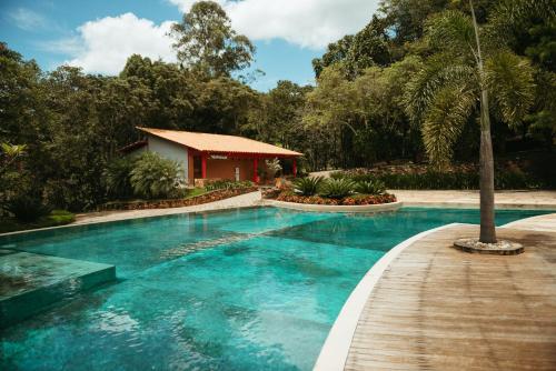 瓜佩Cachoeira do Macuco Boutique Hotel的一座带木道的游泳池,位于房子旁边