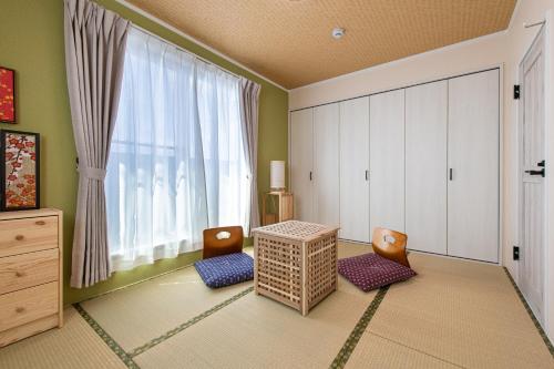 东京Ici Japon Village的客房设有桌子、两把椅子和窗户。