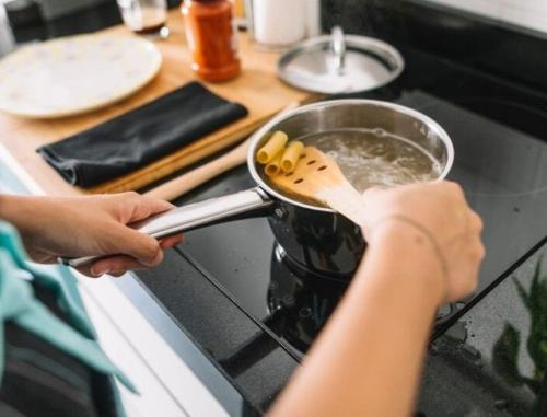 日惹De Patuk Homestay的炉子上的锅里做饭的人