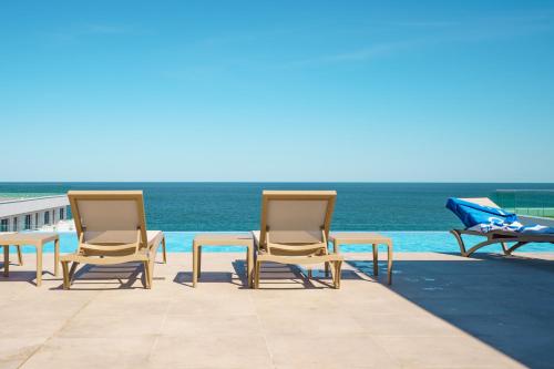 北马马亚-讷沃达里Royale Sundance 305 Infinity Beach Pool & Spa Mamaia Nord的一组椅子和一张桌子,靠近大海