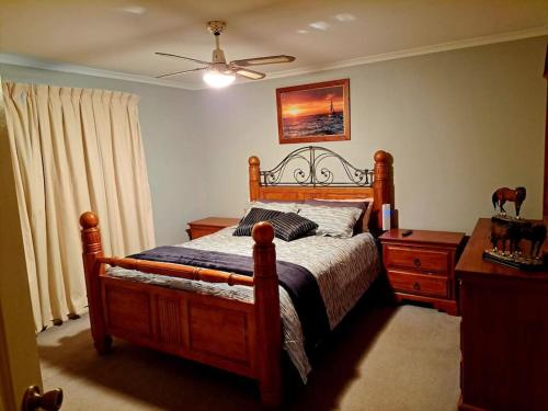 塔南达Welcome to Schnippen Inn.的一间卧室配有一张木床、一个梳妆台和吊扇。