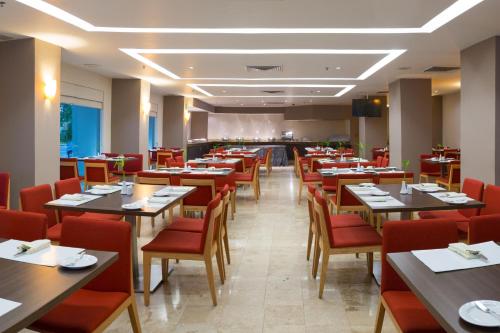 比亚埃尔莫萨Courtyard by Marriott Villahermosa Tabasco的餐厅设有木桌和红色椅子