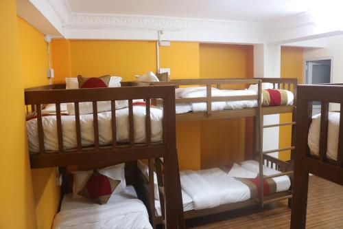加德满都Nepalaya Home Hostel的带黄色墙壁的客房内的三张双层床