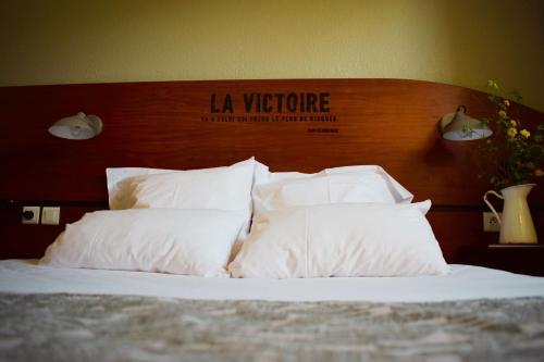 图卢兹Sporting House Hôtel的一张带白色枕头和木制床头板的床