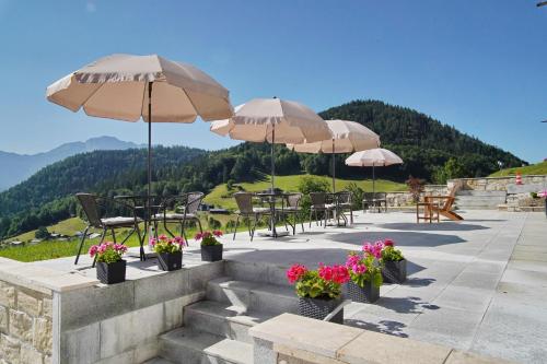 贝希特斯加登贝洛别墅酒店的一个带桌椅、遮阳伞和鲜花的庭院