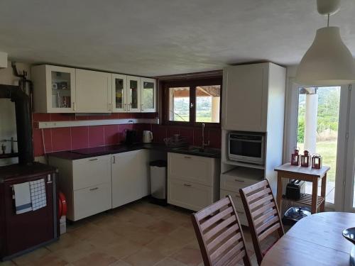 马洛塞讷Petit Paradis的厨房配有白色橱柜和桌椅