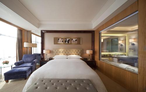 常州常州富力喜来登酒店的一间卧室配有一张大床和一张蓝色椅子
