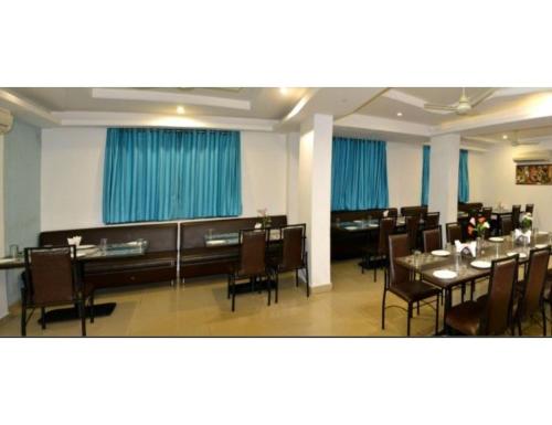 那格浦尔Hotel Flora Inn, Nagpur的一间配备有桌椅的用餐室和蓝色窗帘