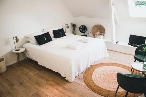 RuttenB&B in woonboerderij vlakbij Lemmer的卧室配有一张带黑色枕头的大型白色床。