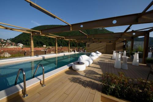 布拉索夫Radisson Blu Aurum Hotel, Brasov的木制甲板上的带白色椅子的游泳池