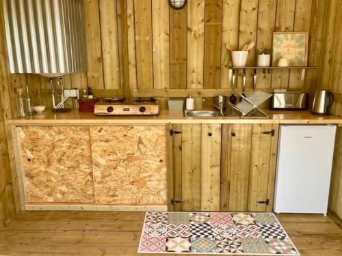 里戈尔Tente Glamping nature et océan, Rogil的厨房设有木墙和带水槽的台面。
