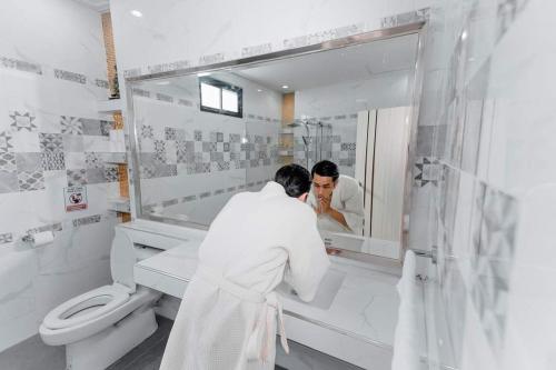 Sawankhalok69YIng Yang House 3BR Sawankhalok的男人在浴室里看着镜子