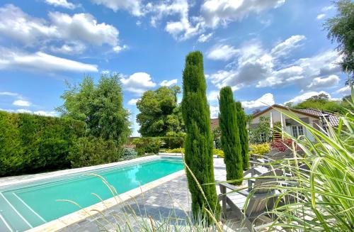 Courcelles-SapicourtLa Maison de Manolie的一座房子前面的游泳池,里面种植了柏树