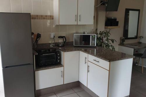 谢普斯敦港Acacia's Rest的厨房配有白色橱柜、微波炉和冰箱。