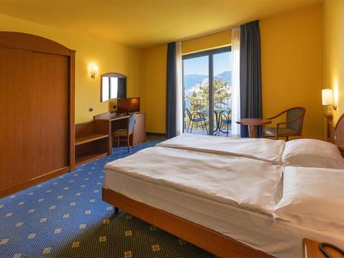 马尔切西内Natur Resort Panorama的配有一张床、一张书桌和一扇窗户的酒店客房