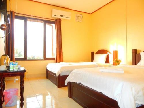 万荣DokPhut Guesthouse的酒店客房设有两张床和窗户。
