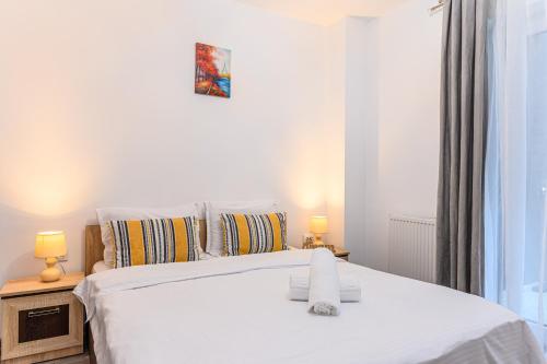 布拉索夫JAD - Comfortable Family Apartments - Coresi的卧室配有带两盏灯的白色床