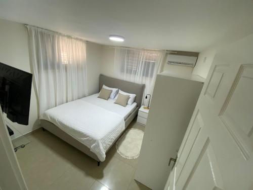 谢莫纳城יחידת קורל בלב הגליל העליון coral unit的一间白色卧室,配有床和电视