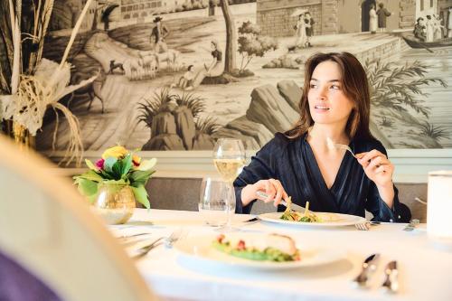 沃韦Grand Hotel du Lac - Relais & Châteaux的坐在餐桌上吃食物的女人