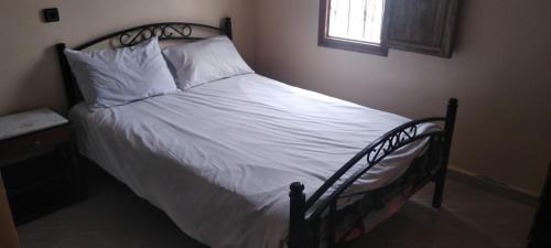 Tan-Tan PlageAppart avec terrasse El Ouatia Tan Tan Plage的卧室内的一张带白色床单和枕头的床