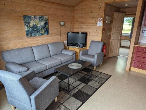 Vigeland索斯特兰假日公园的客厅配有沙发、两把椅子和电视