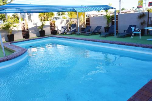 麦凯Rover Motel的一个带蓝伞和椅子的游泳池