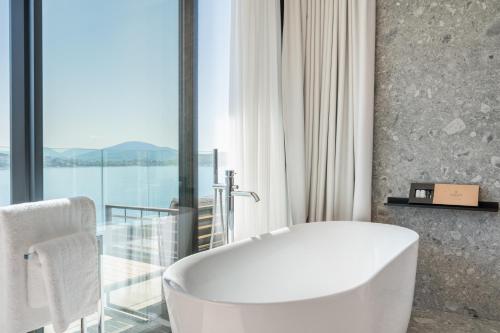 萨兰达Yacht Premium Hotel的带窗户的浴室内的白色浴缸