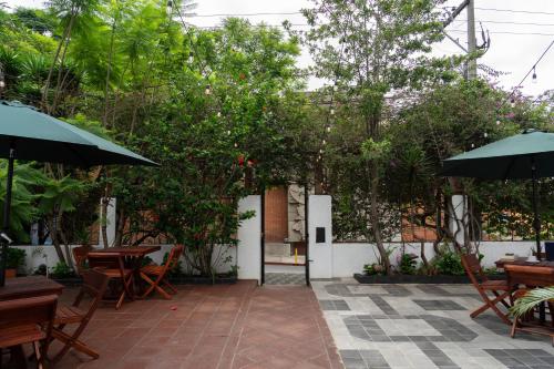 危地马拉RIO HOSTEL的一个带桌子、遮阳伞和树木的庭院