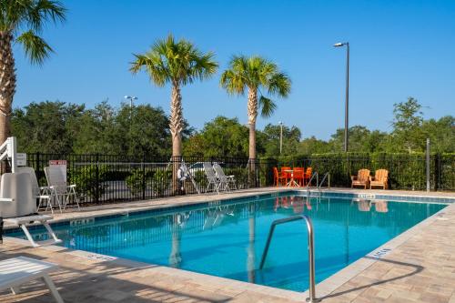 奥兰多SPOT X Hotel Orlando Intl Dr by The Red Collection的一个带椅子的游泳池,棕榈树