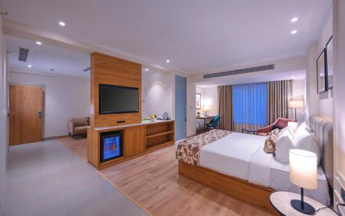 阿格拉Royale Sarovar Portico Agra的配有一张床和一台平面电视的酒店客房