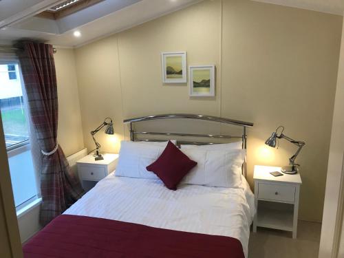 拉尔Hot Tub Accommodation North Wales Caravan的一间卧室配有一张床,两台桌子上放着两盏灯