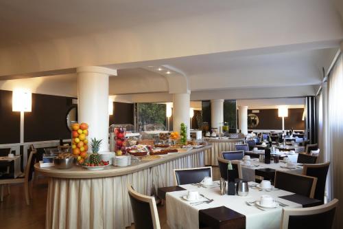 卢卡阿尔伯格席琳酒店的一间设有白色桌椅的餐厅和一间酒吧