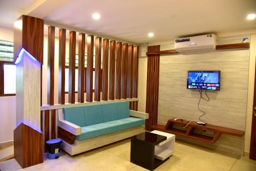 玛纳多迪ROYAL CASTLE HOTEL的客厅设有蓝色长椅和电视。