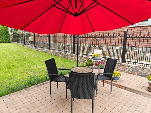 阿利图斯Vakaro Namai的庭院里配有桌椅和红伞