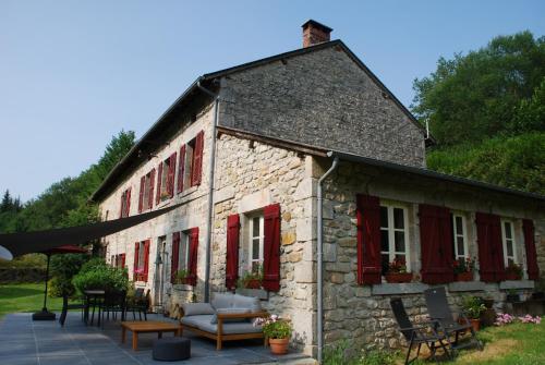 Saint-MoreilLe Moulin de la Farge B&B的一座古老的石头建筑,设有红色百叶窗