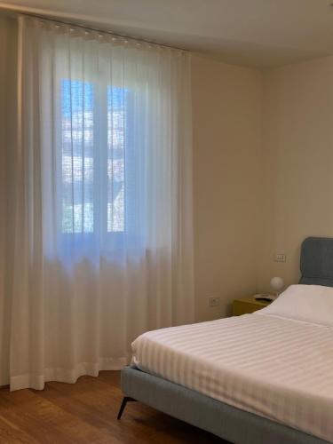 乌尔比诺Urbino Apartment - Urban Retreat的一间卧室配有床和白色窗帘的窗户
