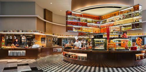新加坡Grand Copthorne Waterfront的餐厅设有酒吧,厨师为您准备食物