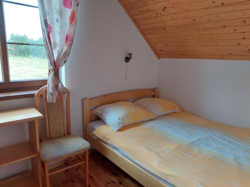雷恩Domki nad jeziorem - Posiadłość Nad Zatoką的卧室配有床、椅子和窗户。