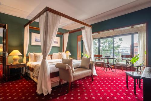 内罗毕萨洛瓦士丹利酒店的一间卧室配有一张天蓬床、椅子和一张桌子