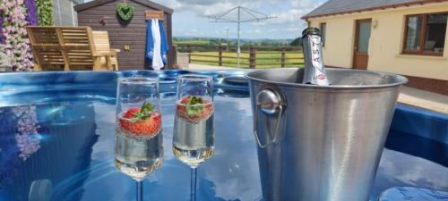 卡马森Sunny Bank- Countryside Escape with Private Hot Tub and countryside views的两杯水和一桶草莓
