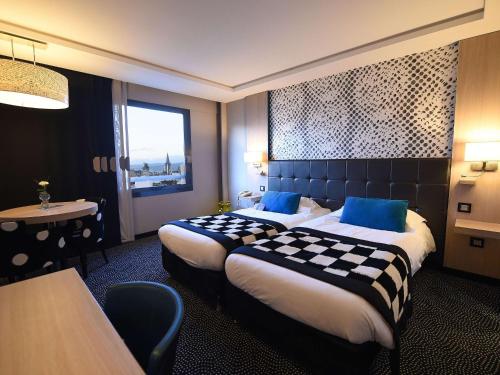 第戎Mercure Dijon Centre Clemenceau的酒店客房设有两张床和一张桌子。