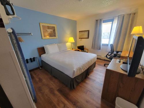格伦代夫SureStay by Best Western Glendive Yellowstone River的一间卧室配有一张床和一张书桌及电视