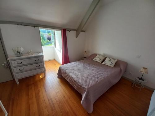 AdéMaison de vacances的一间卧室配有一张床、一个梳妆台和一扇窗户。