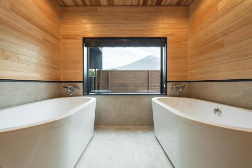富士河口湖Fuji no Sato Alibio的一间带两个白色浴缸和窗户的浴室