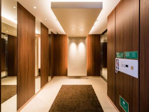 东京Super Hotel Tokyo Kinshicho Ekimae / Vacation STAY 78884的走廊设有木镶板,走廊设有地毯