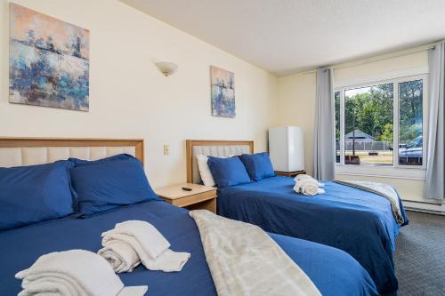 沃萨加比奇海滩Beach Club by Beach1 Motel的卧室内的两张床,配有蓝色的床单和毛巾