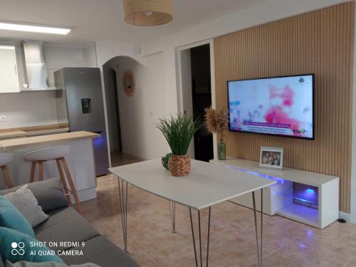 拉皮内达Paraíso beach的客厅配有桌子,墙上配有电视
