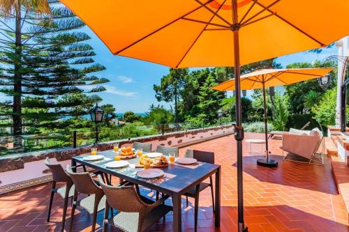 埃斯托利尔Estoril Royal Atlantic Villa with Ocean View的庭院里配有桌椅和遮阳伞
