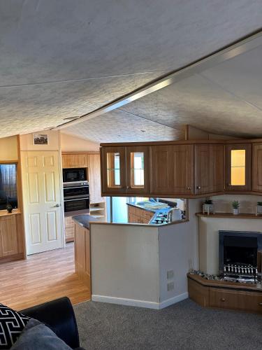 普里茅斯Static Caravan - Plymouth - Costal Location的厨房配有木制橱柜和壁炉。