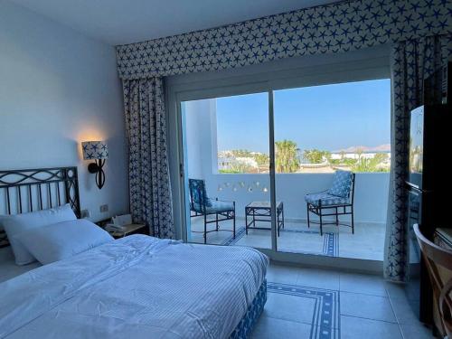 沙姆沙伊赫Azure Retreat - Private Luxury Sea View Apartment的一间卧室配有一张床,阳台配有椅子